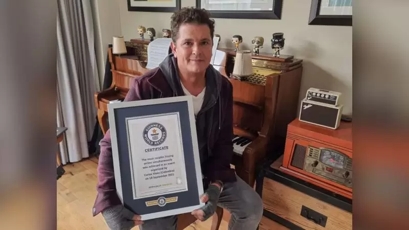 Carlos Vives mostrando el t�tulo de Guinness World Records de la mayor cantidad de parejas bes�ndose online simult�neamente